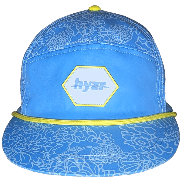 Front view of the Cordelia Deck Hat. Powder blue 7-panel flat brimmed hat, with a floral print and a yellow rope.