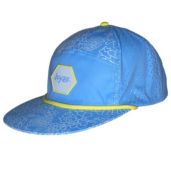 45 degree view of the Cordelia Deck Hat. Powder blue 7-panel flat brimmed hat, with a floral print and a yellow rope.
