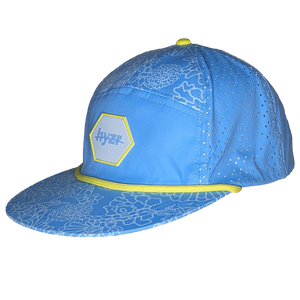 45 degree view of the Cordelia Deck Hat. Powder blue 7-panel flat brimmed hat, with a floral print and a yellow rope.